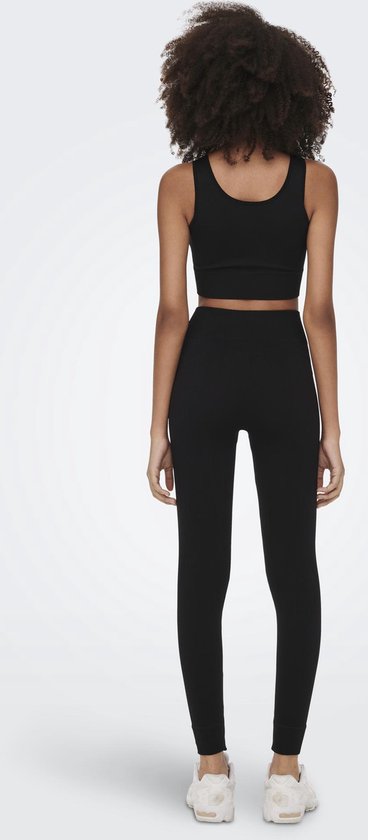 Zicht op de achterkant van een model met zwart sport-set, inclusief nauwsluitende legging met hoge taille.