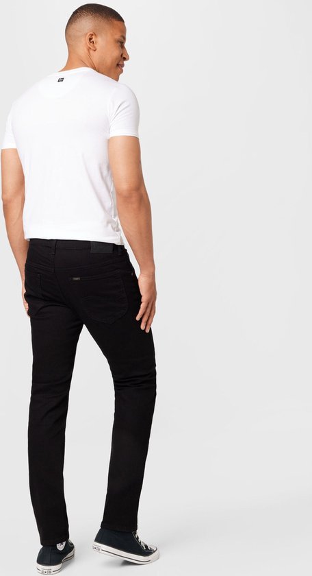 Achterkant van een man met een witte t-shirt en zwarte jeans.