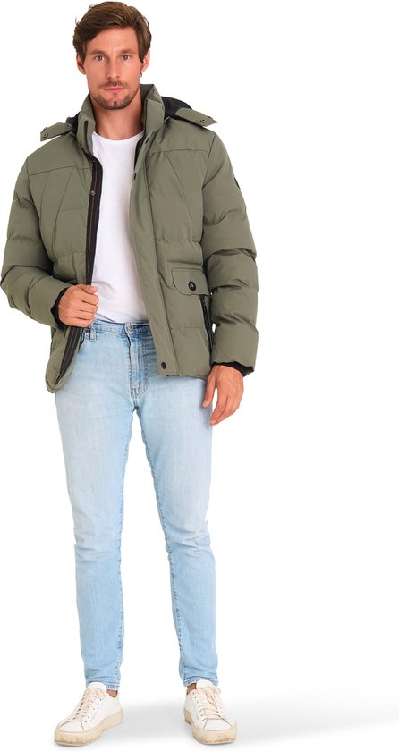 Man met lichtbruine spijkerbroek en olijfgroene winterjas, witte t-shirt, witte sneakers.