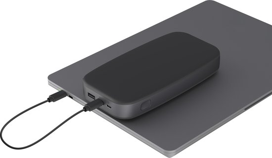 Donkergrijze powerbank ligt op een open laptop en wordt opgeladen via een USB-C kabel.