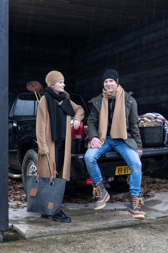 Man en vrouw in winterkleding met mutsen en sjaals, zittend op de achterbank van een pick-up truck.