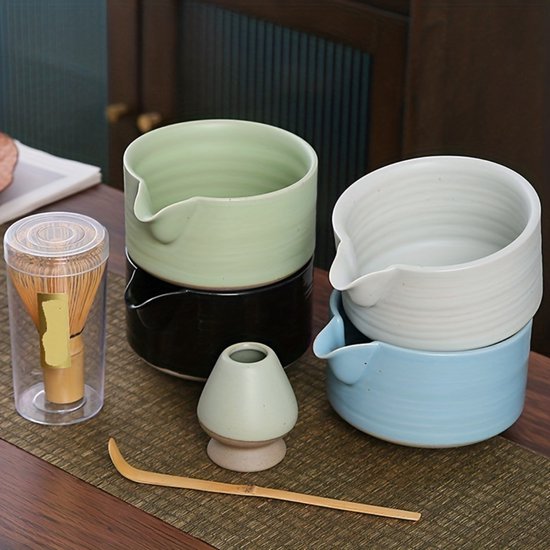 Meerdere matcha kommen in groen, wit en blauw, met klopper in doorzichtige houder.