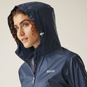 Close-up van een model met krullend haar dat de capuchon van een donkerblauwe regenjas omhoog doet.