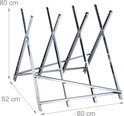 Op de grond staat een inklapbare metalen zaagbok met afmetingen van 80 cm hoogte, 82 cm breedte en 80 cm lengte.