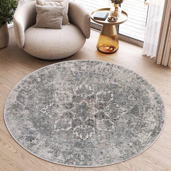 Tapis rond gris à motif floral sur un parquet, à côté d'un fauteuil.