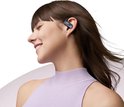 Femme aux yeux fermés porte un écouteur Shokz noir avec crochet d'oreille.