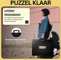 Vrouw met blauwe jas draagt een gesloten zwarte puzzelkoffer met 'PUZZLE READY' erop.