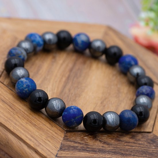 Armband met blauwe lapis lazuli, zwarte onyx en grijze hematiet kralen op een houten ondergrond.