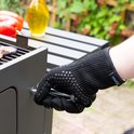 Hand met zwarte, hittebestendige handschoen met siliconen noppen, draait aan een barbecue.