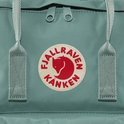 Close-up van het ronde logo op een turquoise Kånken rugzak.