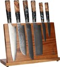 Een houten messenblok met zes Japanse messen met damastpatroon en unieke handvatten van hout en zwarte epoxy.