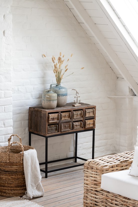 Een sfeervolle zithoek met een mand, een linnen handdoek en een houten meubel met lades.