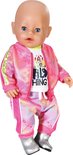 Pop met blauwe ogen, gekleed in een witte t-shirt en roze trainingsbroek met print. Zilveren laarsjes.