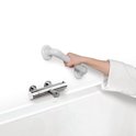 Een persoon pakt een witte badkamer handgreep met ribbelpatroon vast, naast een kraan.