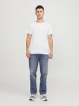 Man in wit T-shirt met ronde hals en spijkerbroek.