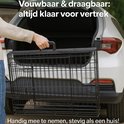 Une personne charge une cage noire en fil dans le coffre d'une voiture.