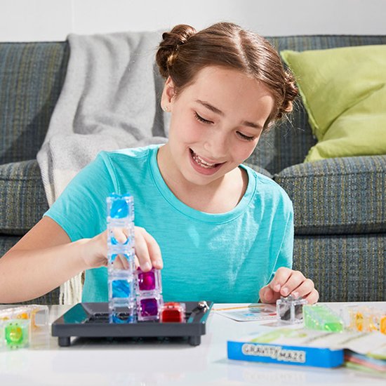 Meisje met bruine knotjes speelt met een transparante, gekleurde toren van het spel Gravity Maze.