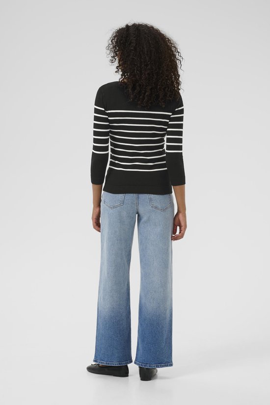 Model met de rug naar de camera, draagt een zwarte trui met horizontale witte strepen en driekwart mouwen, gecombineerd met jeans.