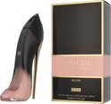 Zwarte parfumdoos met roze band en 'Good Girl Blush Elixir' tekst, naast een zwarte en roze stiletto parfumfles met gouden hak.