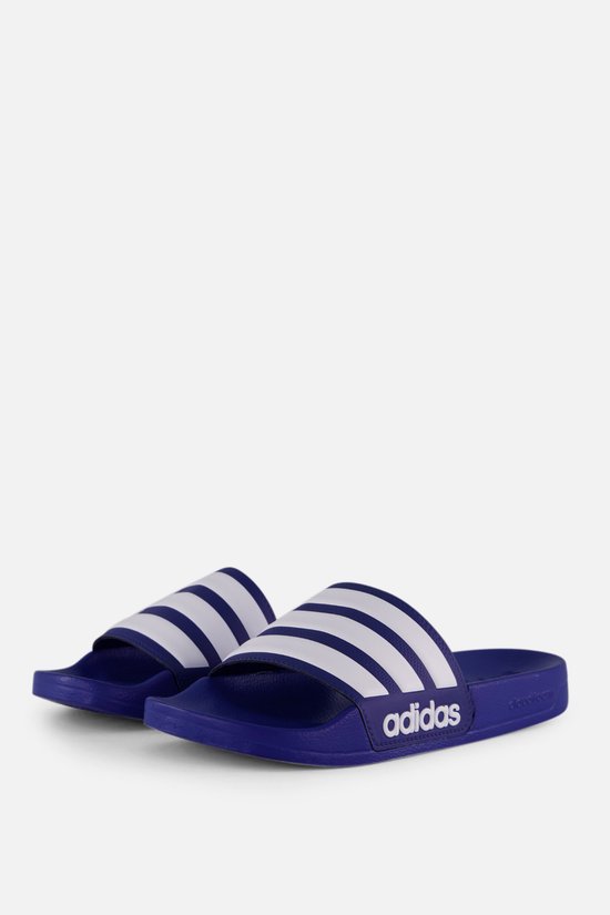 Paar blauwe slippers met drie witte strepen en Adidas-logo.