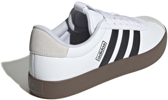 Achterkant van witte Adidas sneakers met zwarte strepen en bruine zool.