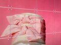 Gros plan d'un large chapeau de paille clair orné d'un grand nœud rose pâle sur fond rose.