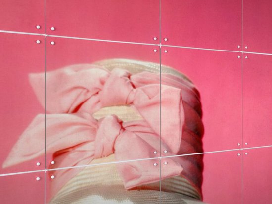 Gros plan d'un large chapeau de paille clair orné d'un grand nœud rose pâle sur fond rose.
