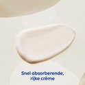Een schep rijke, witte crème op een lichte achtergrond. Tekst: 'Snel absorberende, rijke crème'.