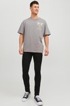 Man met grijze t-shirt met 'Eternal Paradise' print, zwarte skinny jeans en zwart-witte sneakers.
