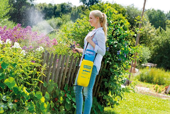 Man sproeit planten met gele Gloria Prima 5 drukspuit in de tuin.