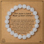 Een armband met ronde, witte edelsteen kralen ligt op een bruin kaartje met de tekst 'Het leven is hard, maar jij bent sterker!'.