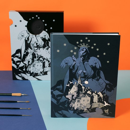 Een boek met op de voorkant een illustratie van een engelachtig figuur boven een dorp, met sterren en een maan. Deels uit de verpakking.