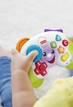 Een babyhandje houdt een Fisher-Price controller vast met ABC-knoppen, cijfers en een lachend gezichtje. Het speelgoed is wit met groene handvatten en oranje accenten.