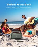 Een groep vrienden geniet van muziek op het strand met de draagbare luidspreker. De luidspreker is aangesloten op een powerbank.