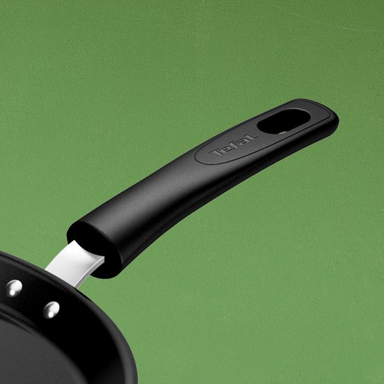 Zwarte Tefal koekenpan steel met ophangoog, verbonden met zilverkleurige klinknagels aan de pan.