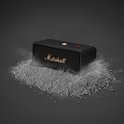 Zwarte Marshall-speaker met goudkleurig logo, omringd door grijs poeder dat opspattend is.