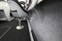 Interieur van een boot met grijs vloertapijt, grijze stoel en grijze wandbekleding.