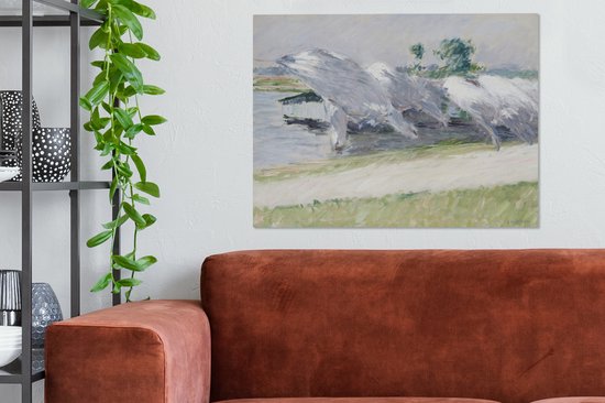 Peinture de linge séchant dans des couleurs claires et douces près de l'eau. L'œuvre est accrochée au-dessus d'un canapé marron.