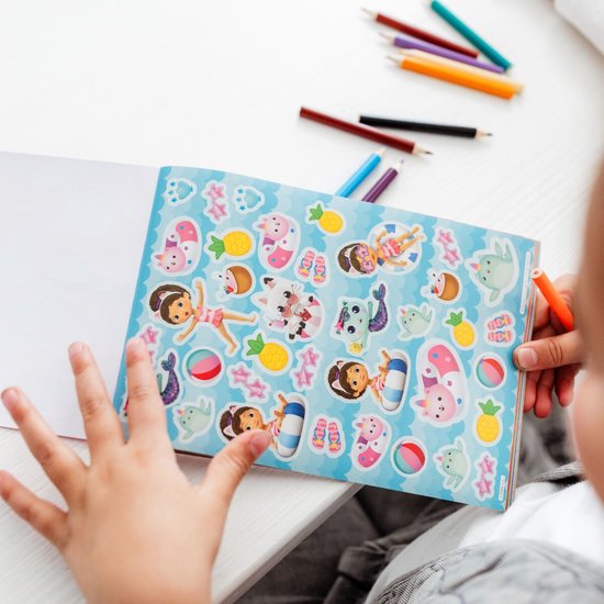 Meisje bekijkt een stickerboek met zeemeermin-thema en afbeeldingen van Gabby en katten.