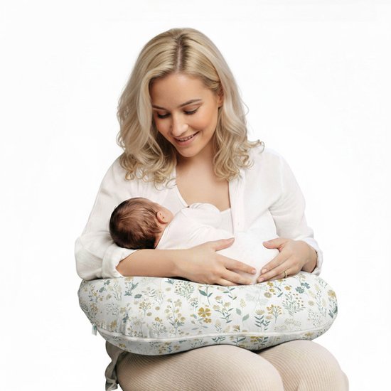Een vrouw met blond haar voedt een baby met een voedingskussen met een bloemenprint.