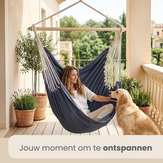 Vrouw zit in een donkerblauwe hangstoel met een hond.