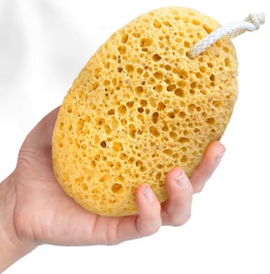 Een lichtgele, ovale badspons met touwtje en honingraatstructuur, vastgehouden in een hand.