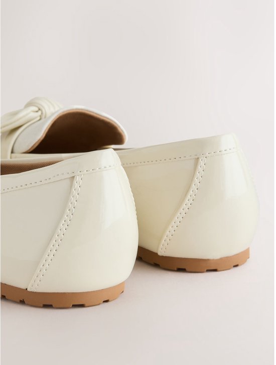 Achterkant van off-white lakleren loafers met stikdetails.