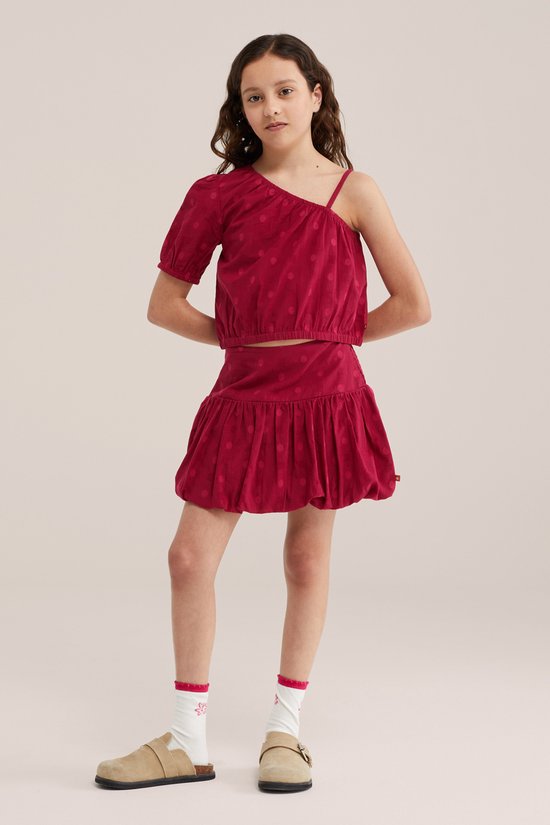 Meisje in een bijpassende set: donkerrode crop top met stippen en een wijde rok met ruches.