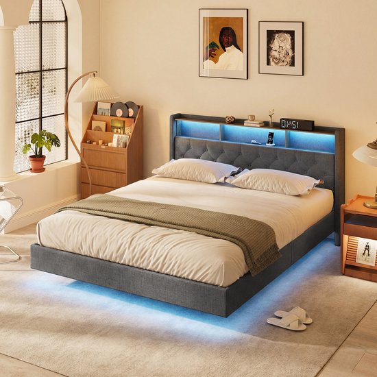 Lit double tapissé gris foncé avec tête de lit boutonnée et éclairage LED intégré. La pièce comprend une table de nuit en bois et un lampadaire.