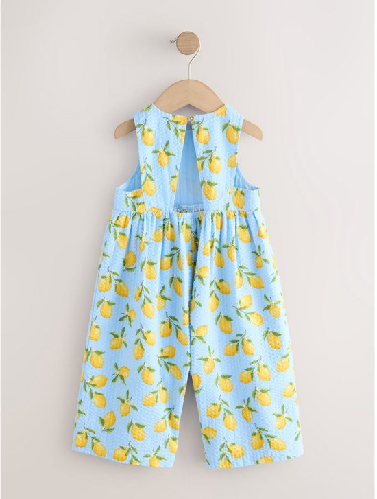 Lichtblauwe playsuit met all-over citroenprint, rug-uitsnijding en knoopsluiting.