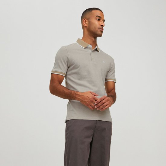 Man draagt een lichtgrijs poloshirt met beige kraag en manchetten met witte bies.