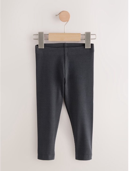 Donkergrijze geribbelde legging hangend aan een kledinghanger.