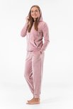 Model in roze fluwelen joggingpak: capuchonvest met rits en joggingbroek.