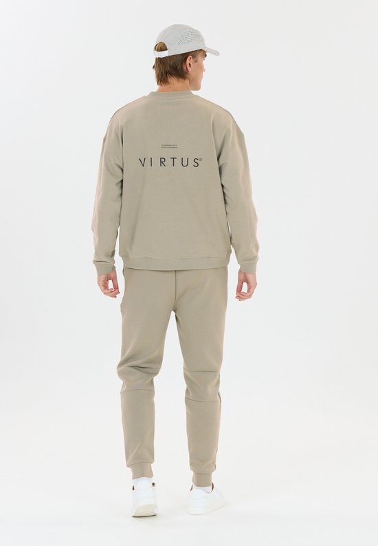 Man in beige trainingsbroek en sweater, rugzijde, met logo op de sweater.